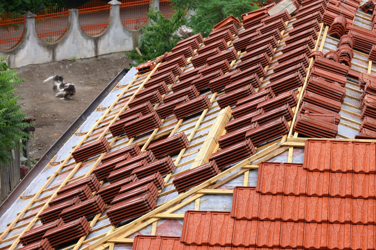Vue en contre-plongée d'une toiture en tuiles terre cuite, avec débord de toit habillé d'un soffit en lambris blanc